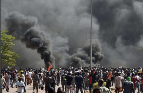 crowd standing near an area attacked by terrorists as thick smoke rises to the sky