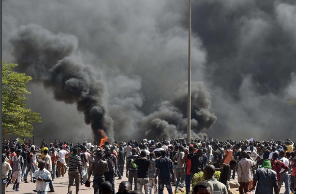 crowd standing near an area attacked by terrorists as thick smoke rises to the sky