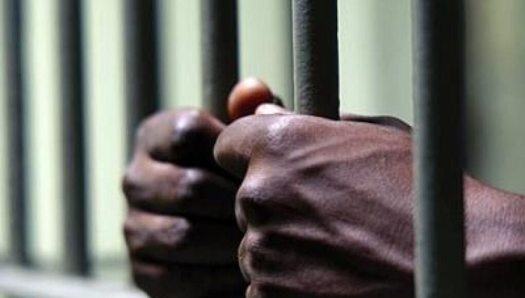 Prisoner's hands on a prison door